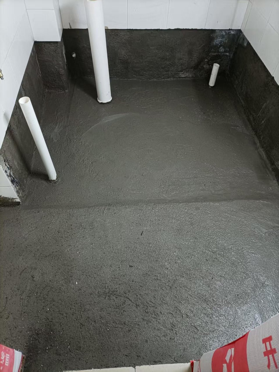 木综厂宿舍卫生间施工中：回填找平完成，墙面伟星咖乐防水层上翻涂刷到位，排污立管预留